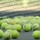 viele Tennisbälle liegen am Netz