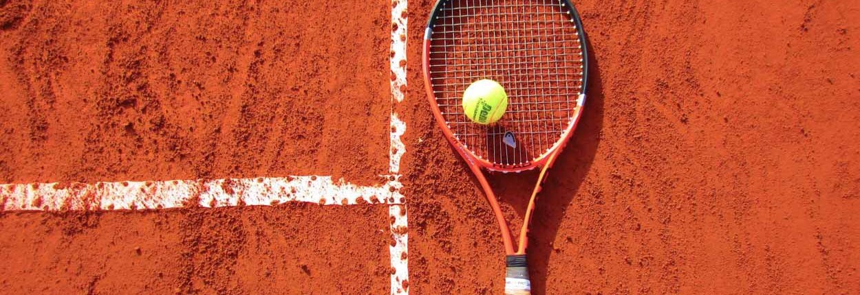 Tennisschläger und Tennisball liegen auf einem Spielfeld